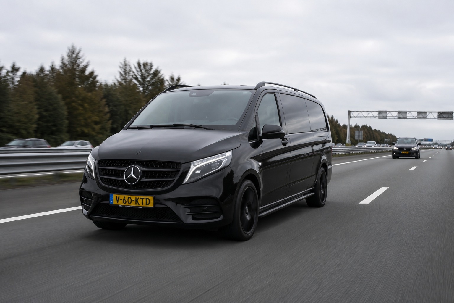 Zwarte Mercedes personenbus die over een snelweg rijdt.